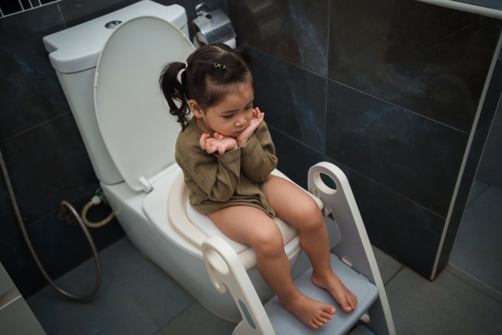child on the toilet sitting correctly with seat reducer and step.